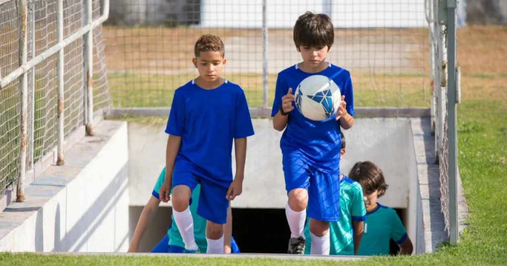Young footballers stepping onto the pitch during youth football development, capturing the early journey, confidence, and dreams of future stars.
